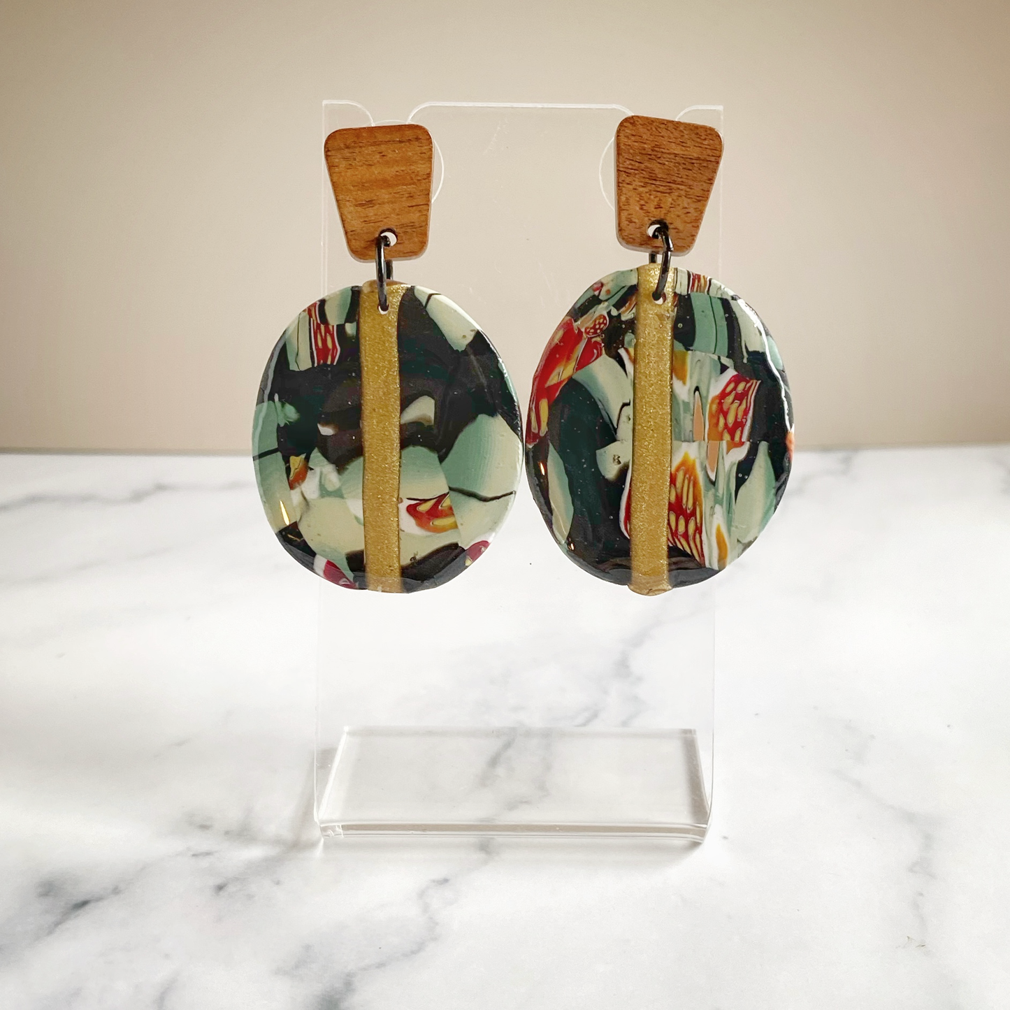 Black Gold and Green Marbled Handmade Polymer Clay Earrings on Transparent earring stand.