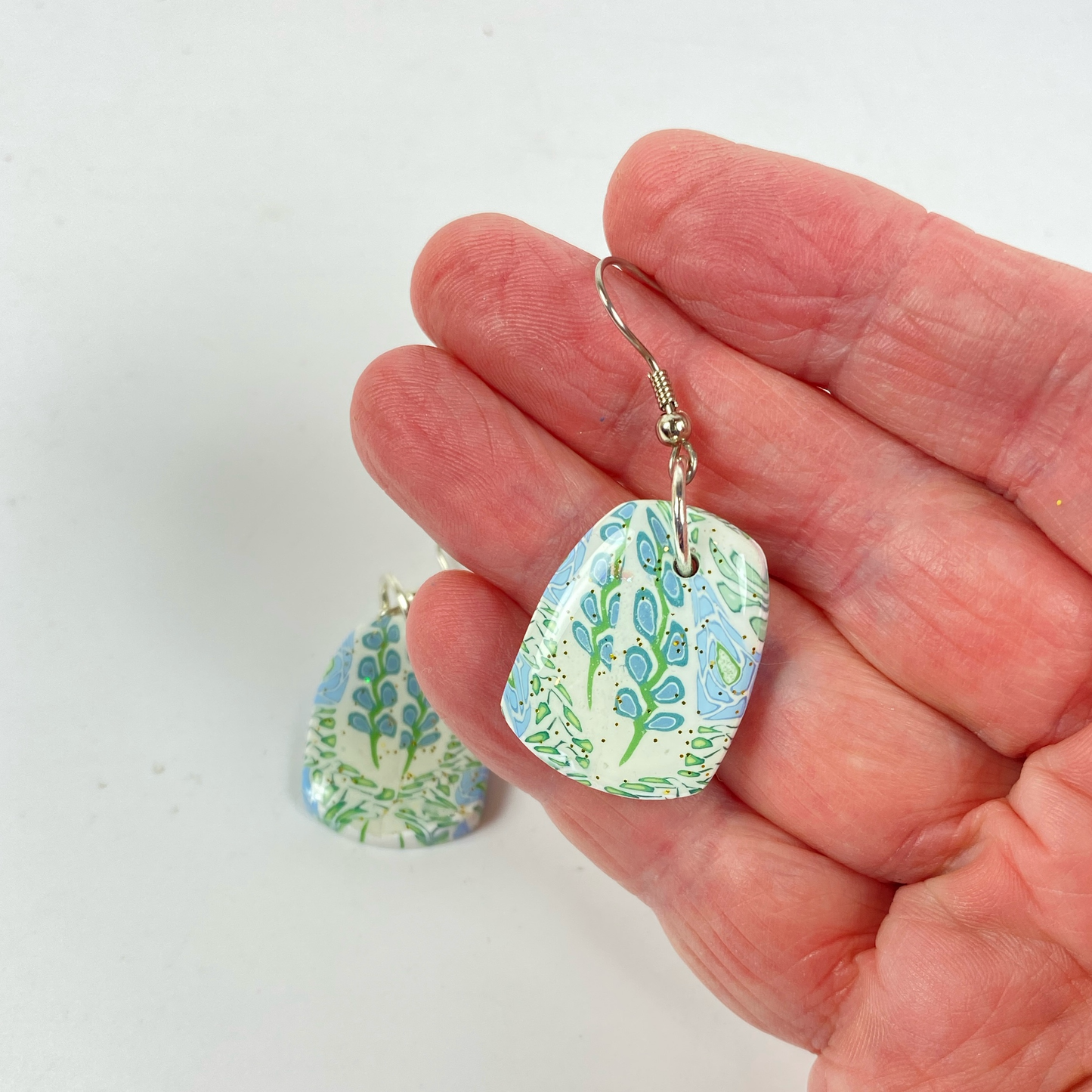 Blue Blossom Handmade Polymer Clay Dangle Earrings handheld for size reference