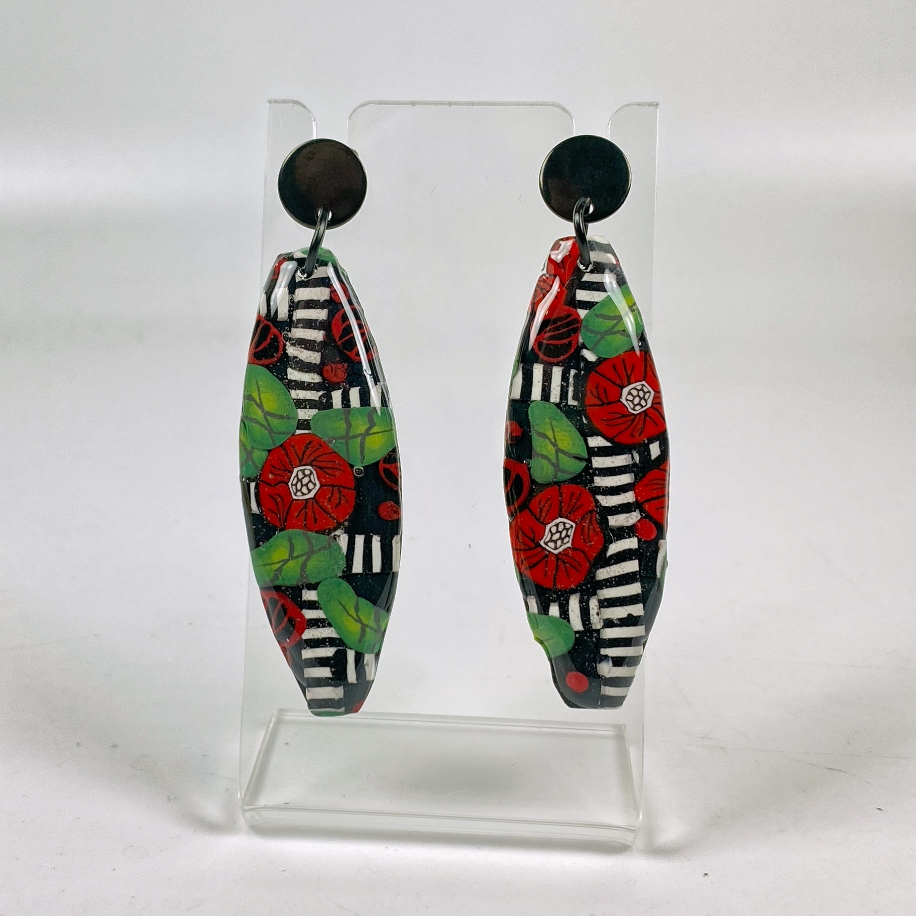 Red Lattice Rose Handmade Polymer Clay Earrings on a clear earrings stand