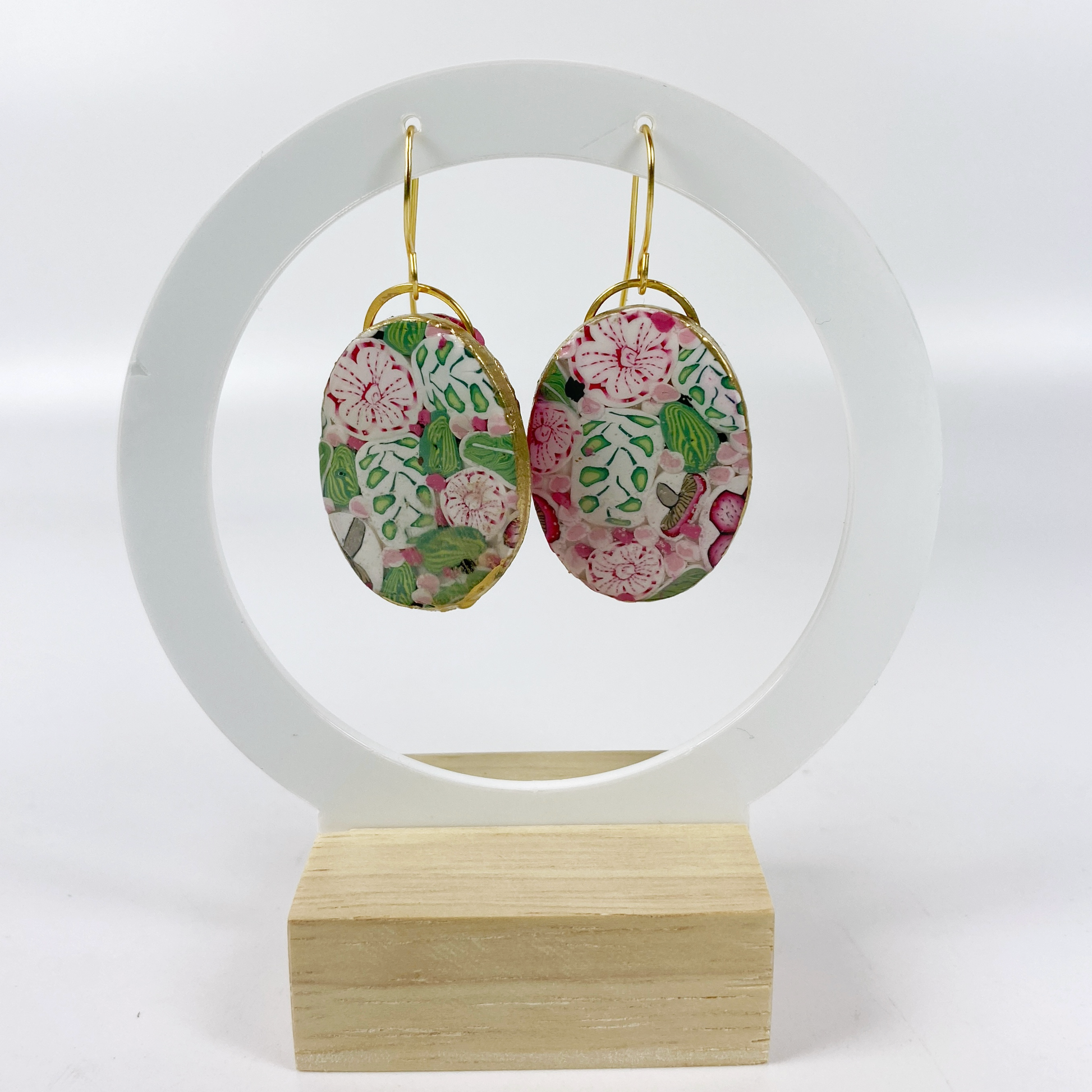 Pink Woodland Handmade Polymer Clay Oval Dangle Earrings on an earring display stand