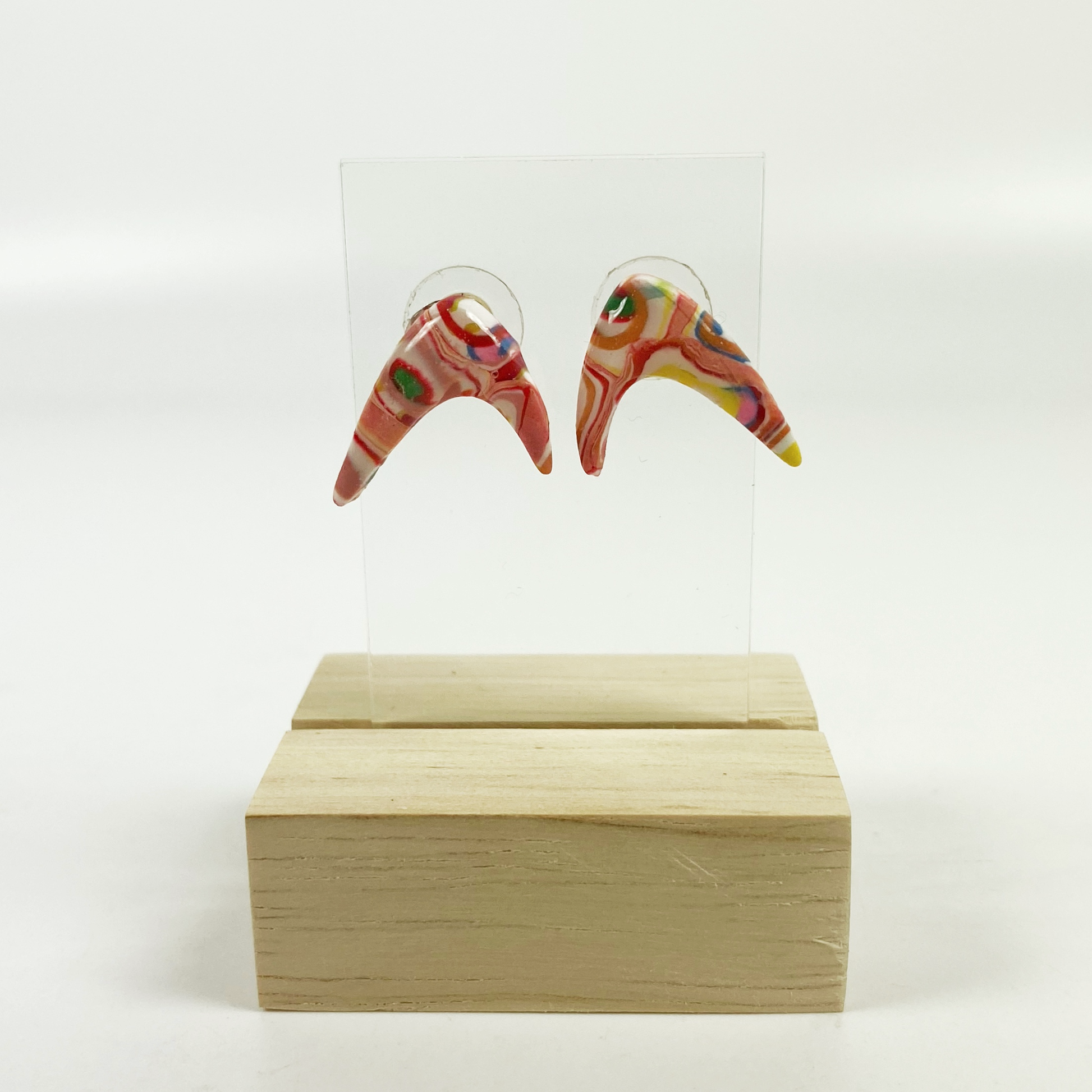 Pink Boomerang Stud Earrings on a wood and acrylic stand