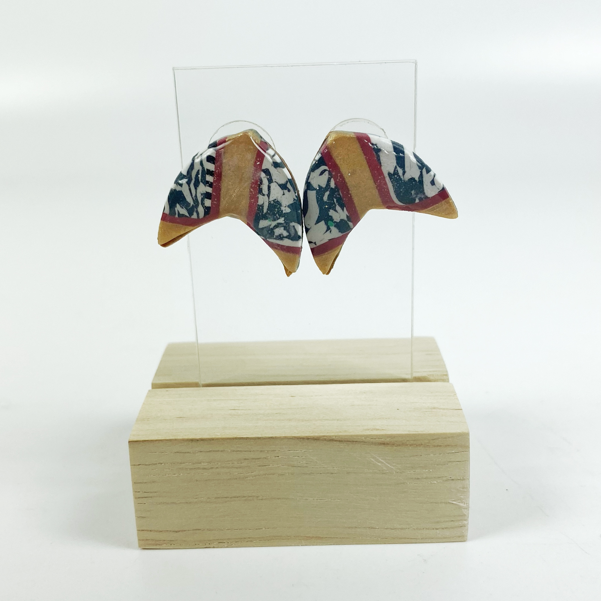 Red and Gold Handmade Polymer Clay Boomerang Stud Earrings on an Acrylic earring display.