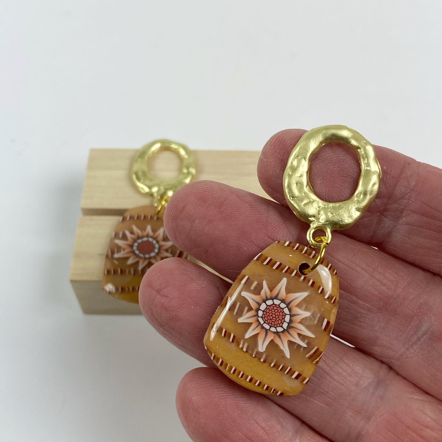 Saffron Daisy Polymer Clay Earrings handheld for size reference.