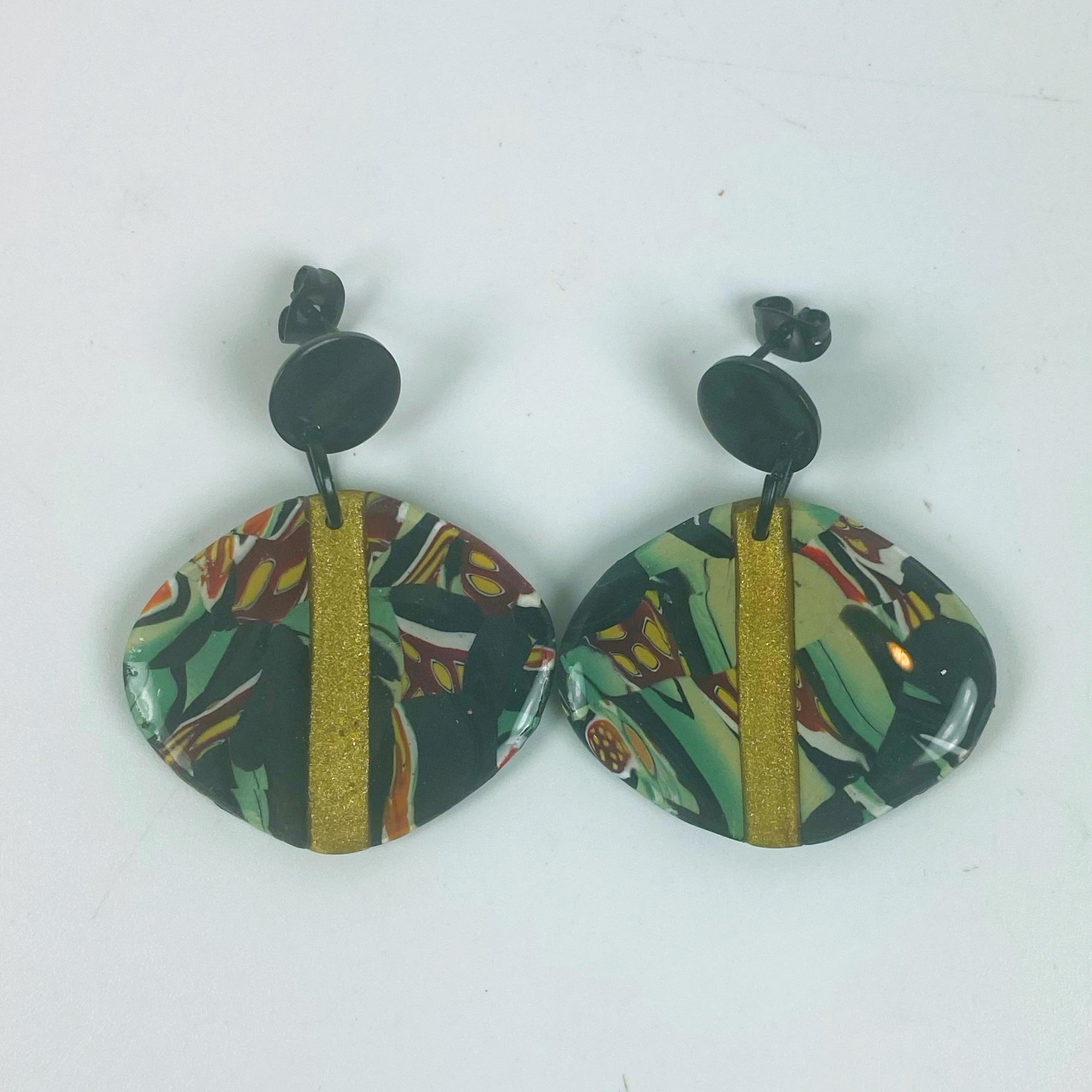 Black Green and Gold Handmade Polymer Clay Dangle Earrings on a neutral background