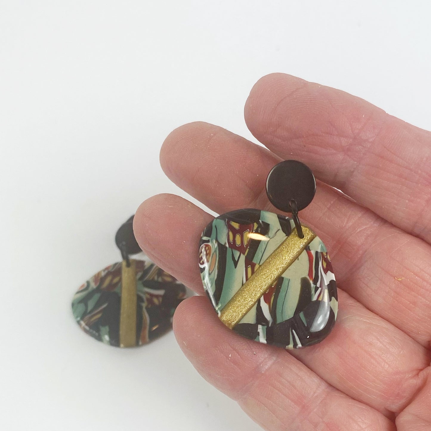 Black Green and Gold Handmade Polymer Clay Dangle Earrings handheld for size reference