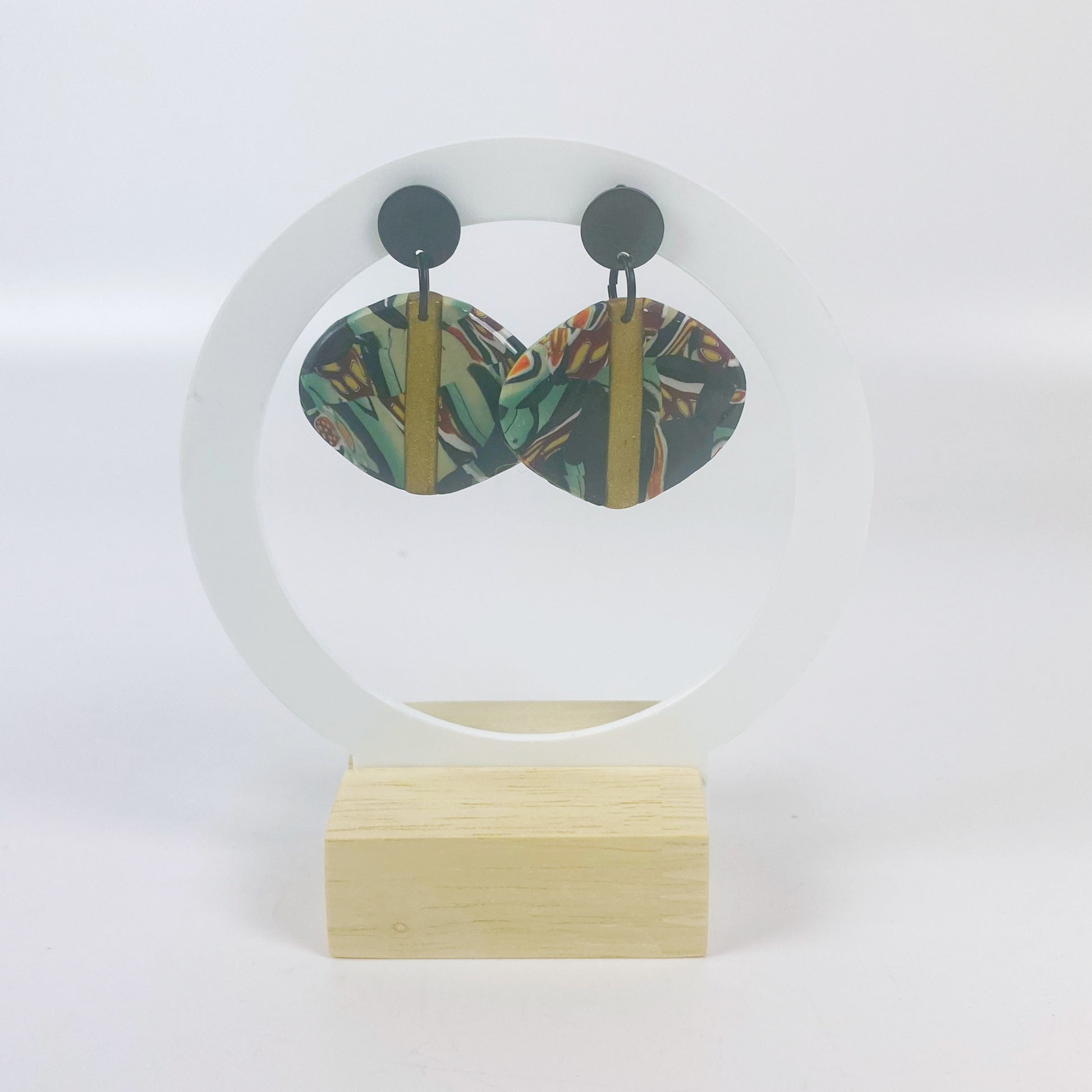 Black Green and Gold Handmade Polymer Clay Dangle Earrings on a white acrylic moon stand