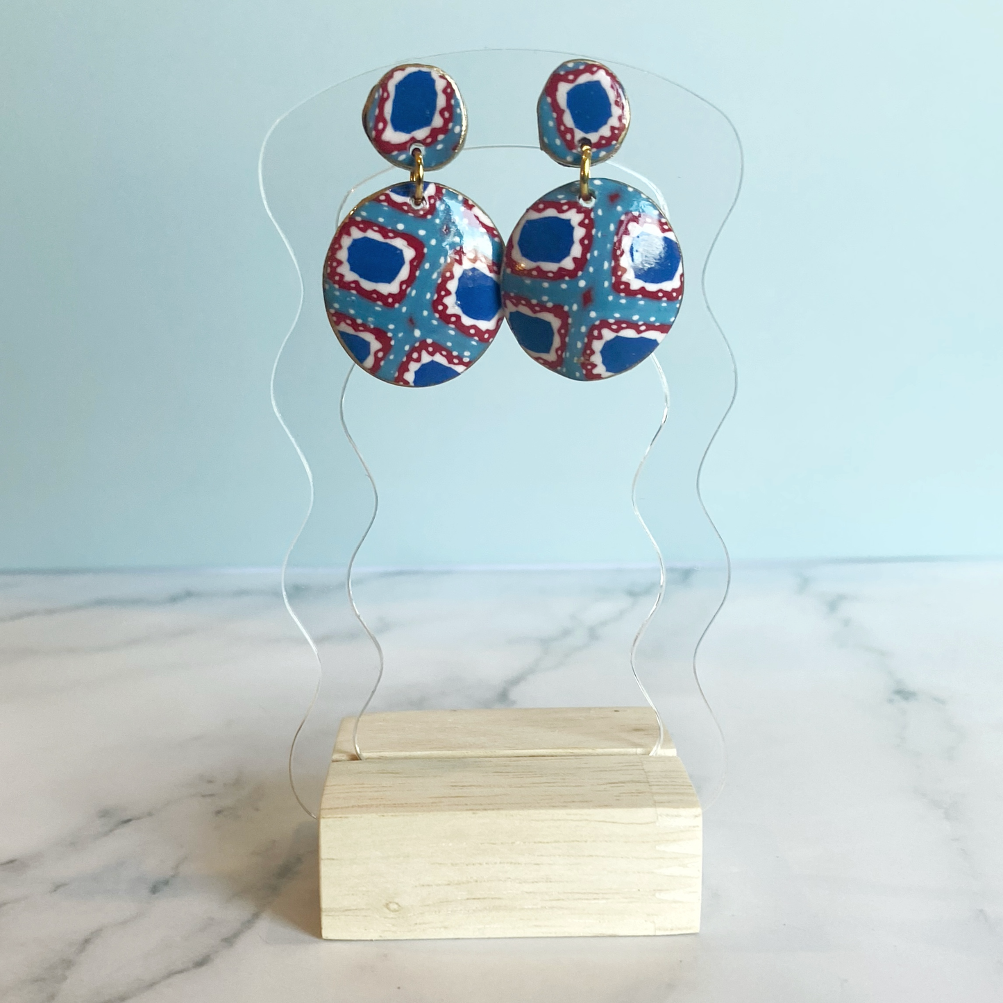 Handmade Polymer Clay Bandana Dangle Earrings hanging from a acrylic display stand