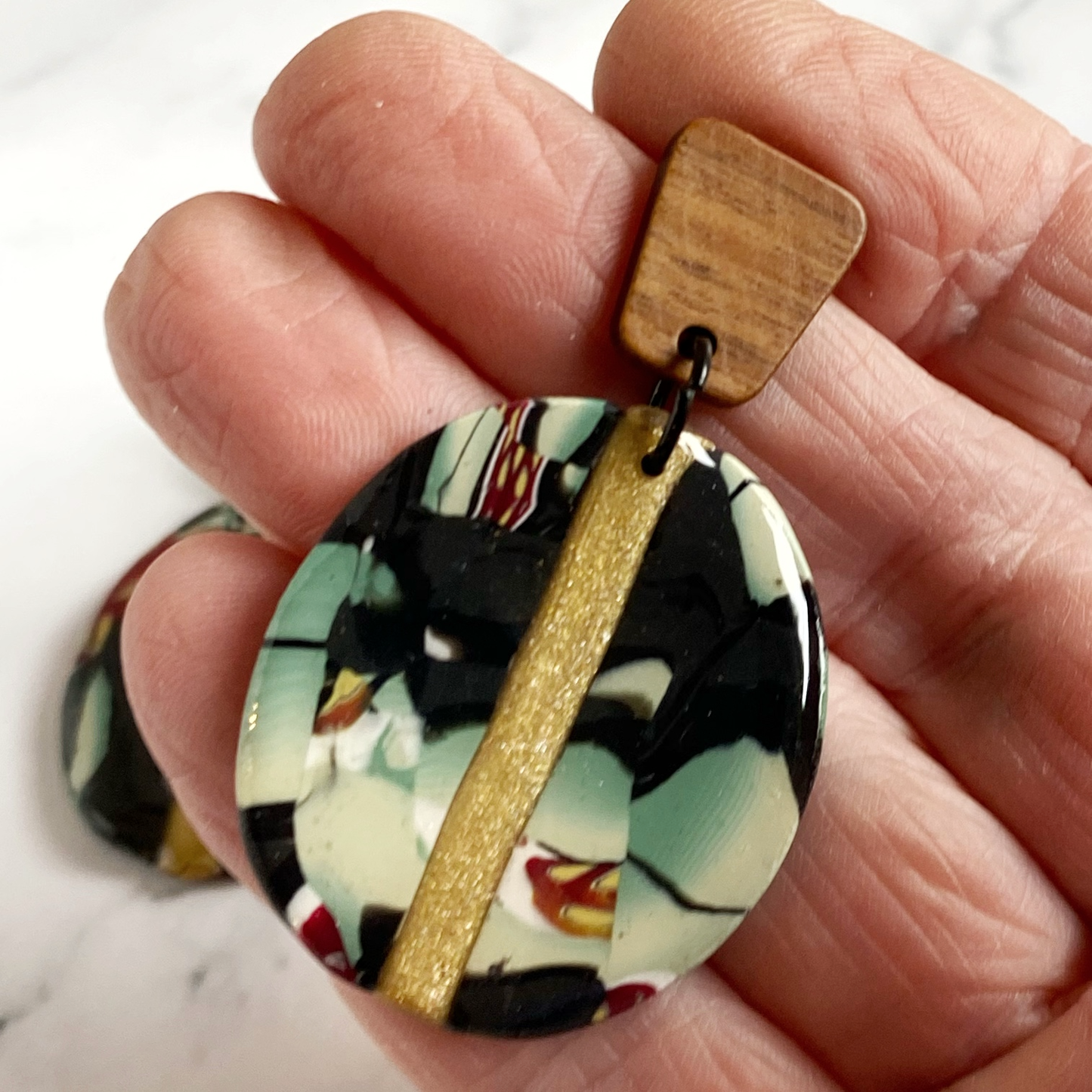 Black Gold and Green Marbled Handmade Polymer Clay Earrings handheld for size reference