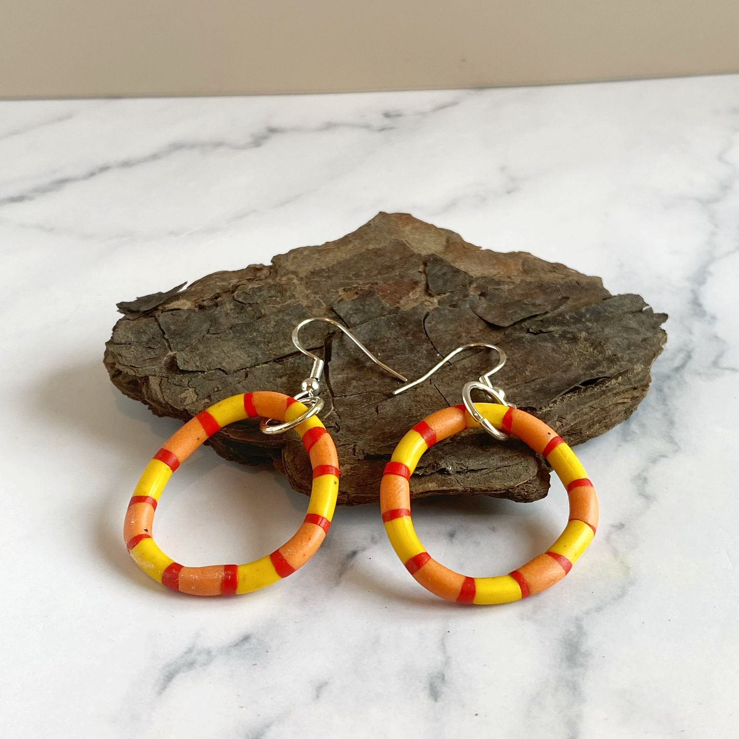 Handmade polymer clay rhythm hoops in red orange and yellow.