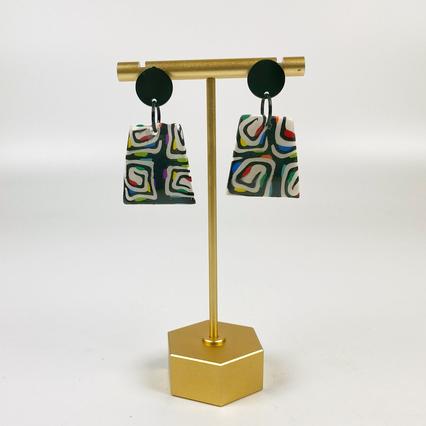 Midnight Spiral Polymer Clay Handmade Dangle Earrings on a brass earring display stand