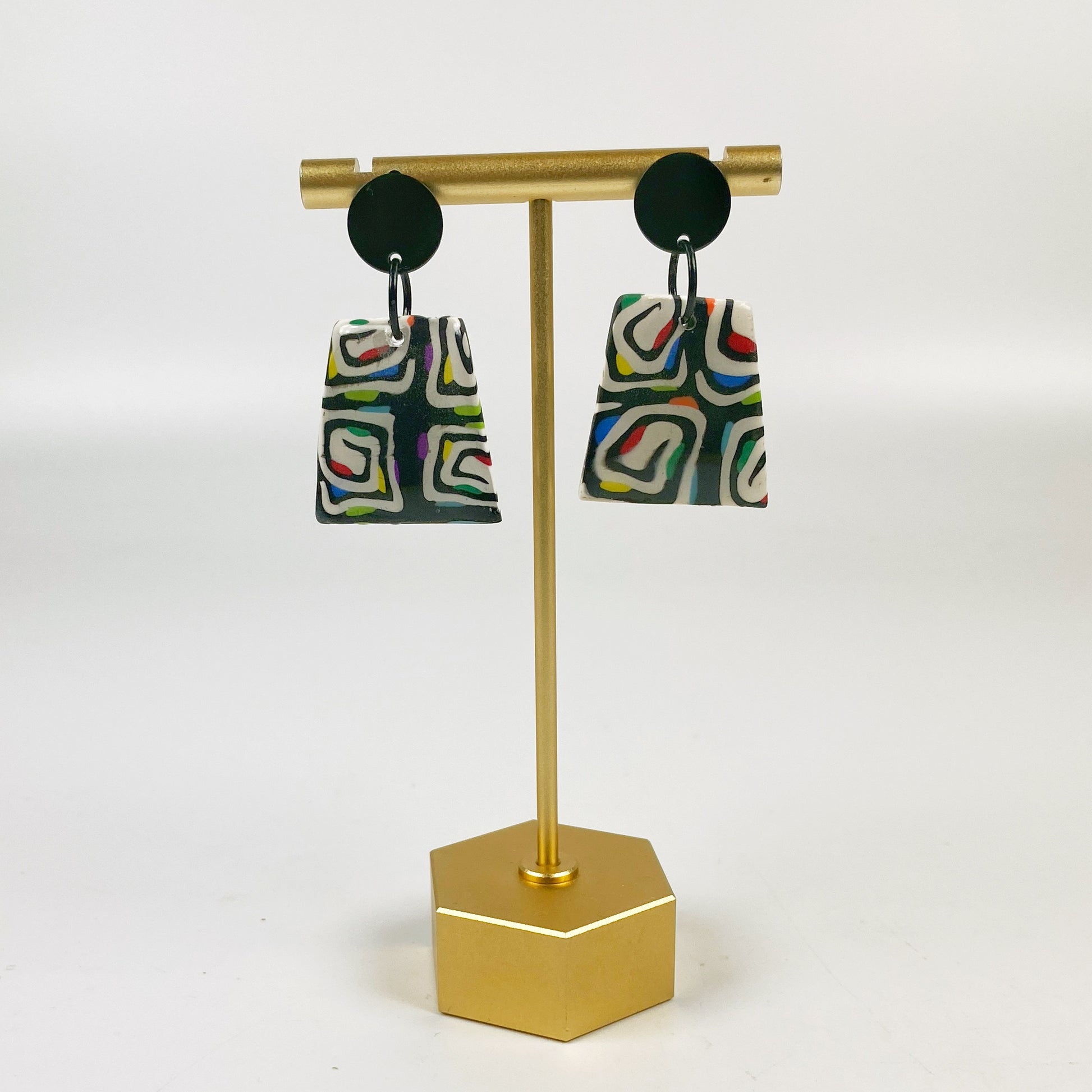Midnight Spiral Polymer Clay Handmade Dangle Earrings on a brass earring display stand