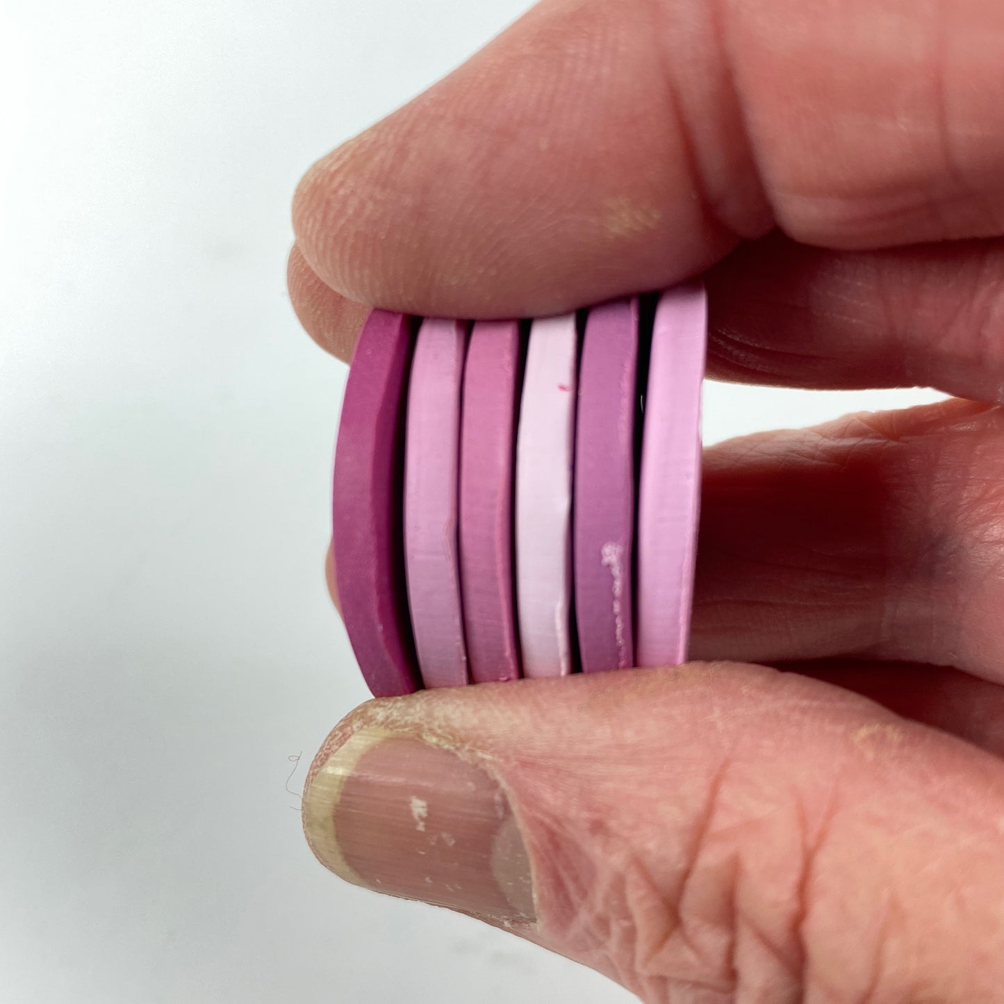  Polymer Clay Candy Hearts Color Palette. Stacked sample discs of each clay color, held in a hand for a side view.