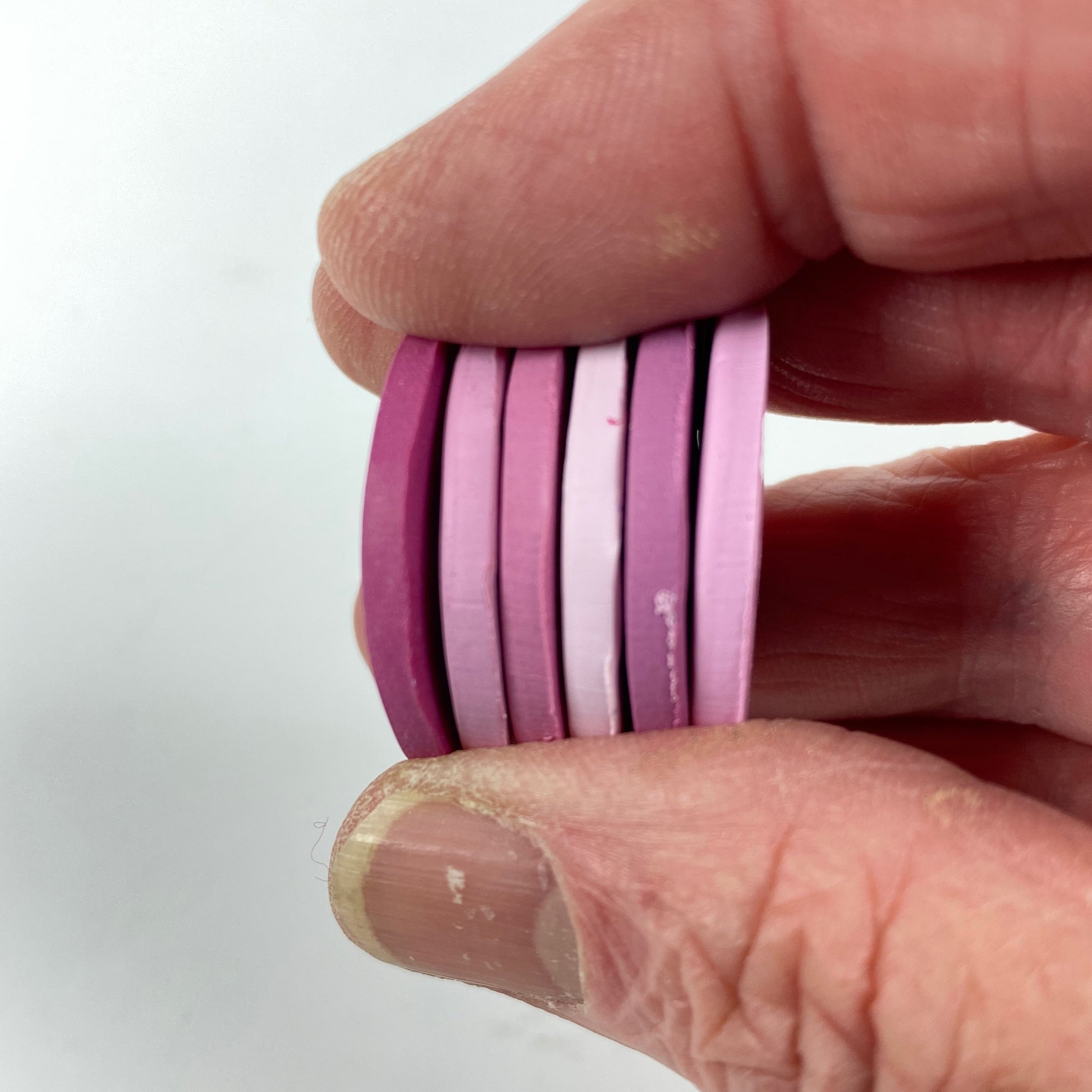  Polymer Clay Candy Hearts Color Palette. Stacked sample discs of each clay color, held in a hand for a side view.