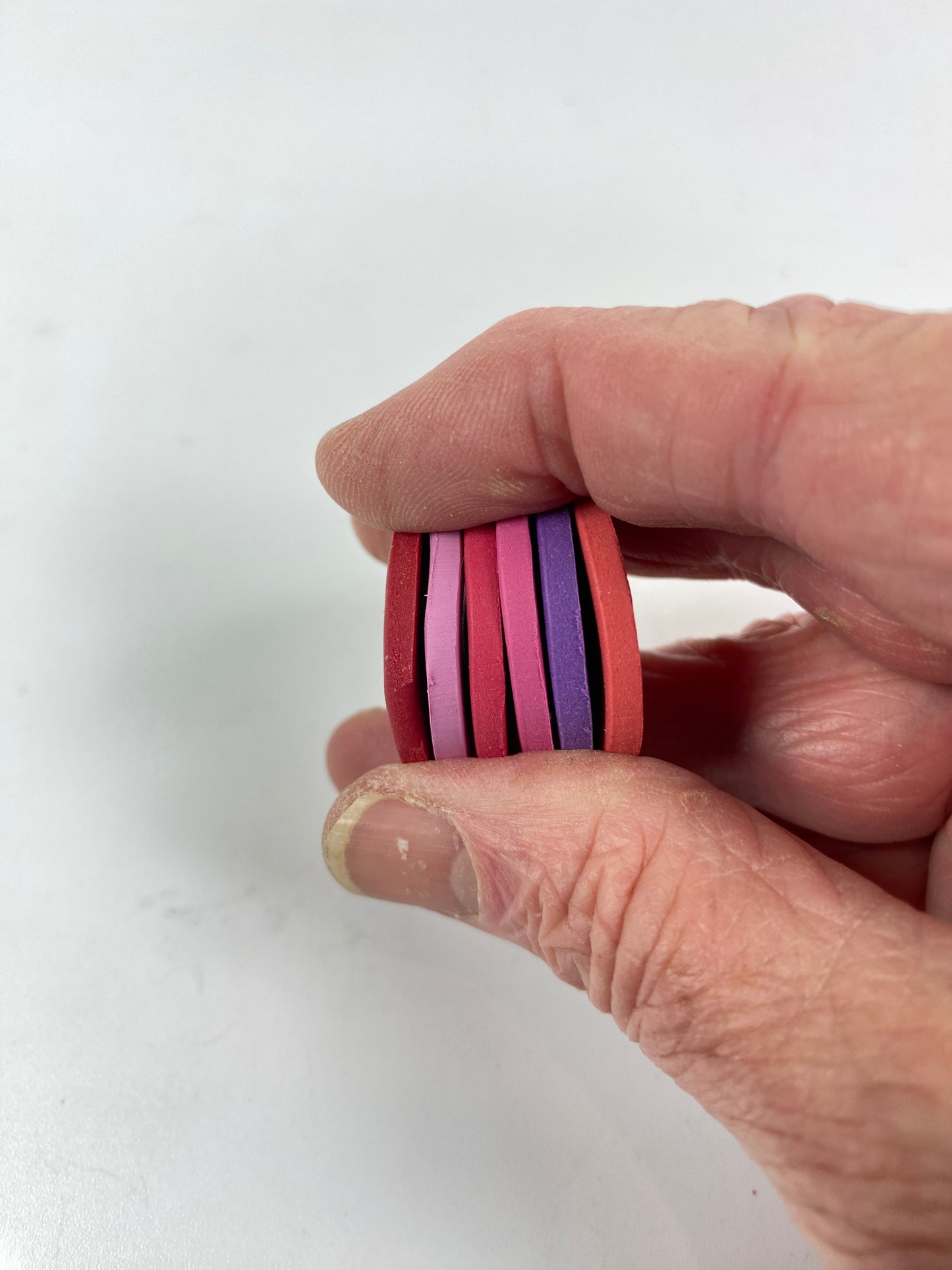 Polymer Clay Fancy Romancy Color Palette. Stacked sample discs of each clay color, held in a hand for a side view