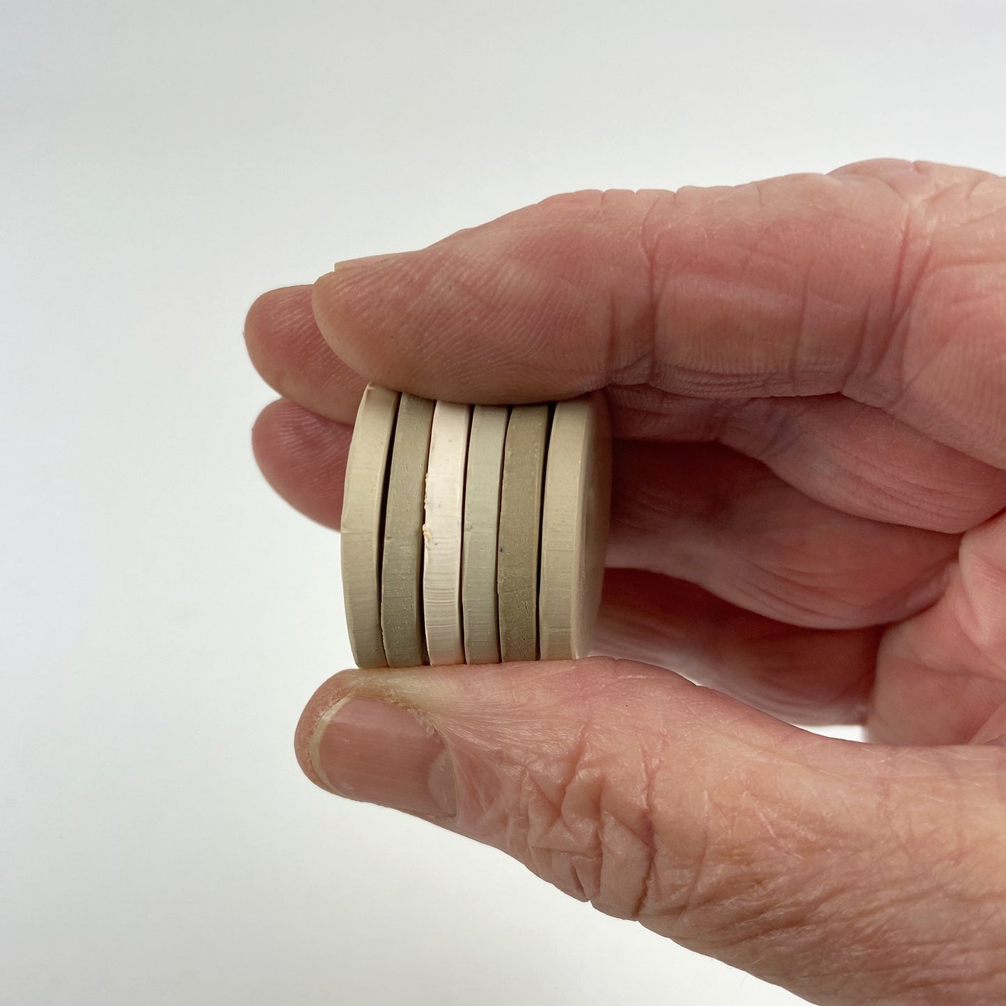 Polymer Clay When you Whisper Color Palette. Stacked sample discs of each clay color, held in a hand for a side view.