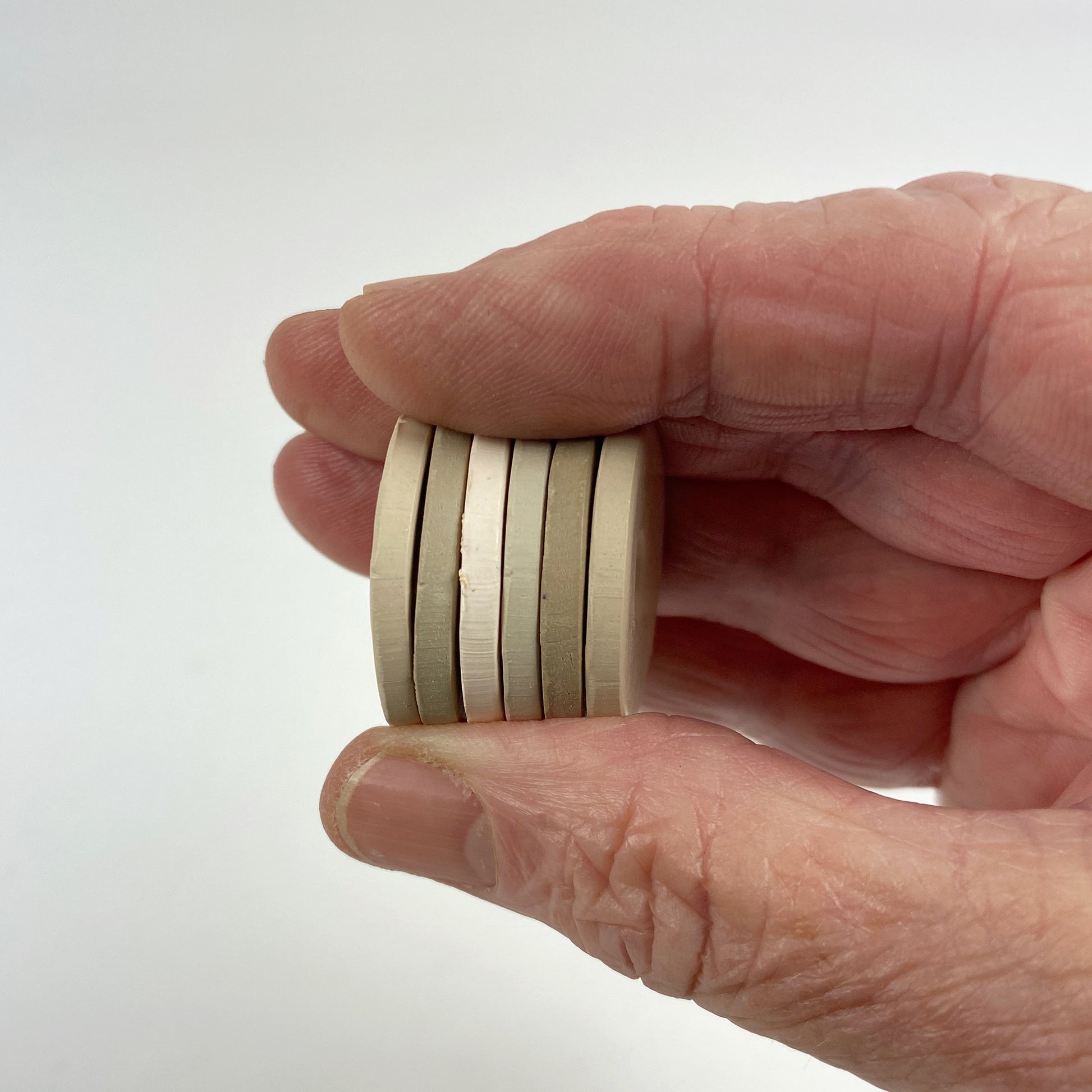 Polymer Clay When you Whisper Color Palette. Stacked sample discs of each clay color, held in a hand for a side view.